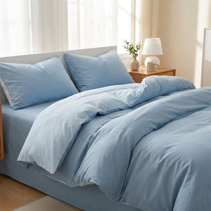 Parure de lit en coton lavé bleu clair sur un lit dans une chambre douce et lumineuse