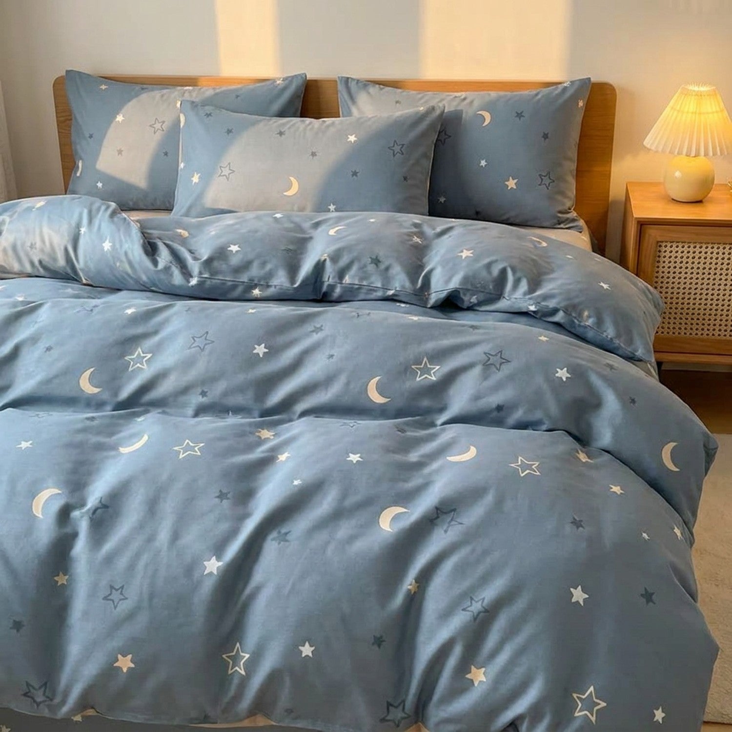Parure de lit enfant en coton bleu à motif étoiles et lune installée sur un lit dans une chambre douce
