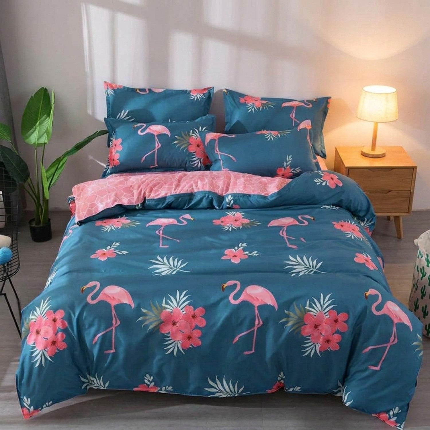 Parure de lit flamant rose sur fond bleu canard dressée sur un lit dans une chambre moderne avec lampe de chevet