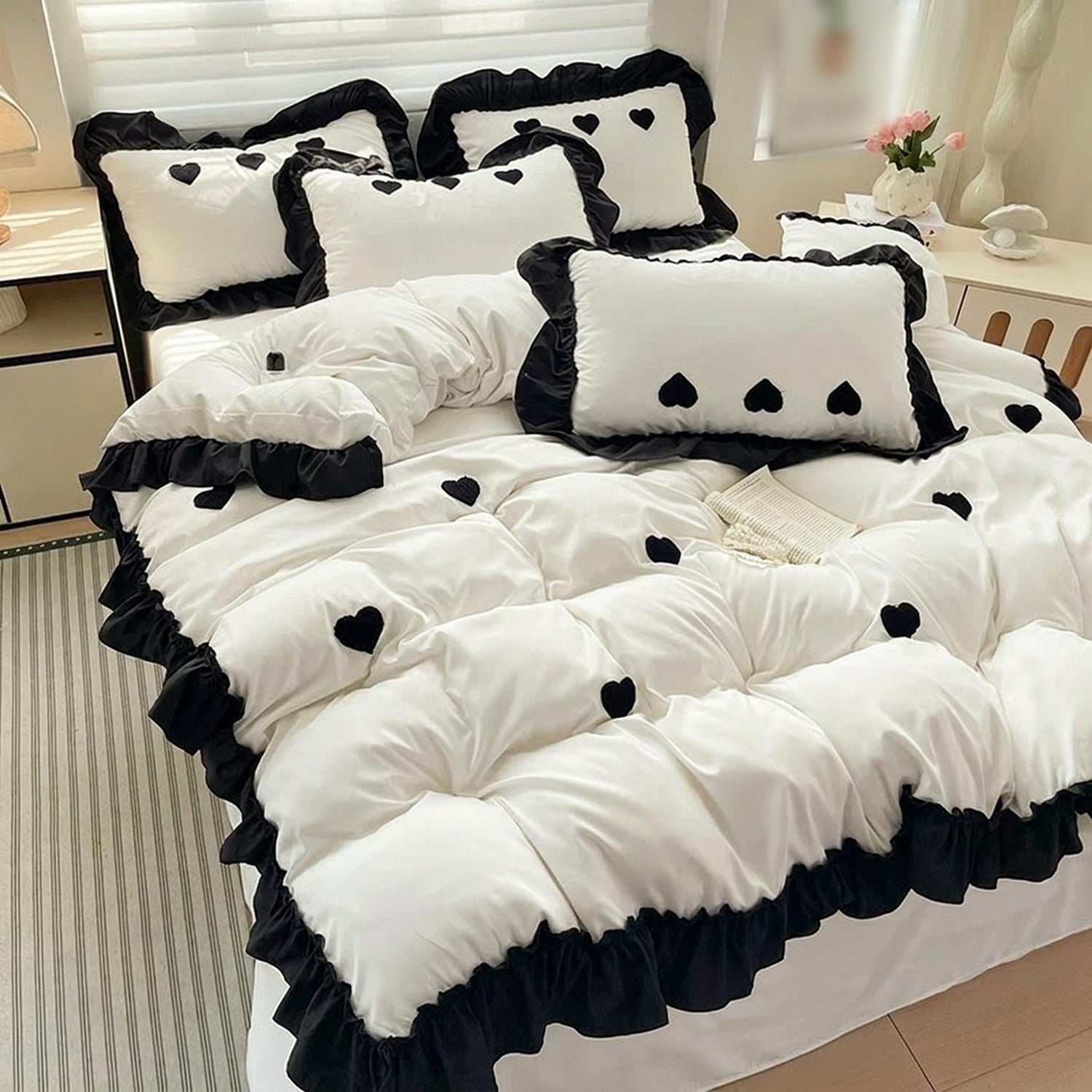 Housse de couette et taies blanches a volants noirs et coeurs brodes sur un lit fait