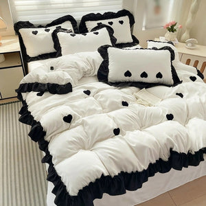 Housse de couette et taies blanches a volants noirs et coeurs brodes sur un lit fait