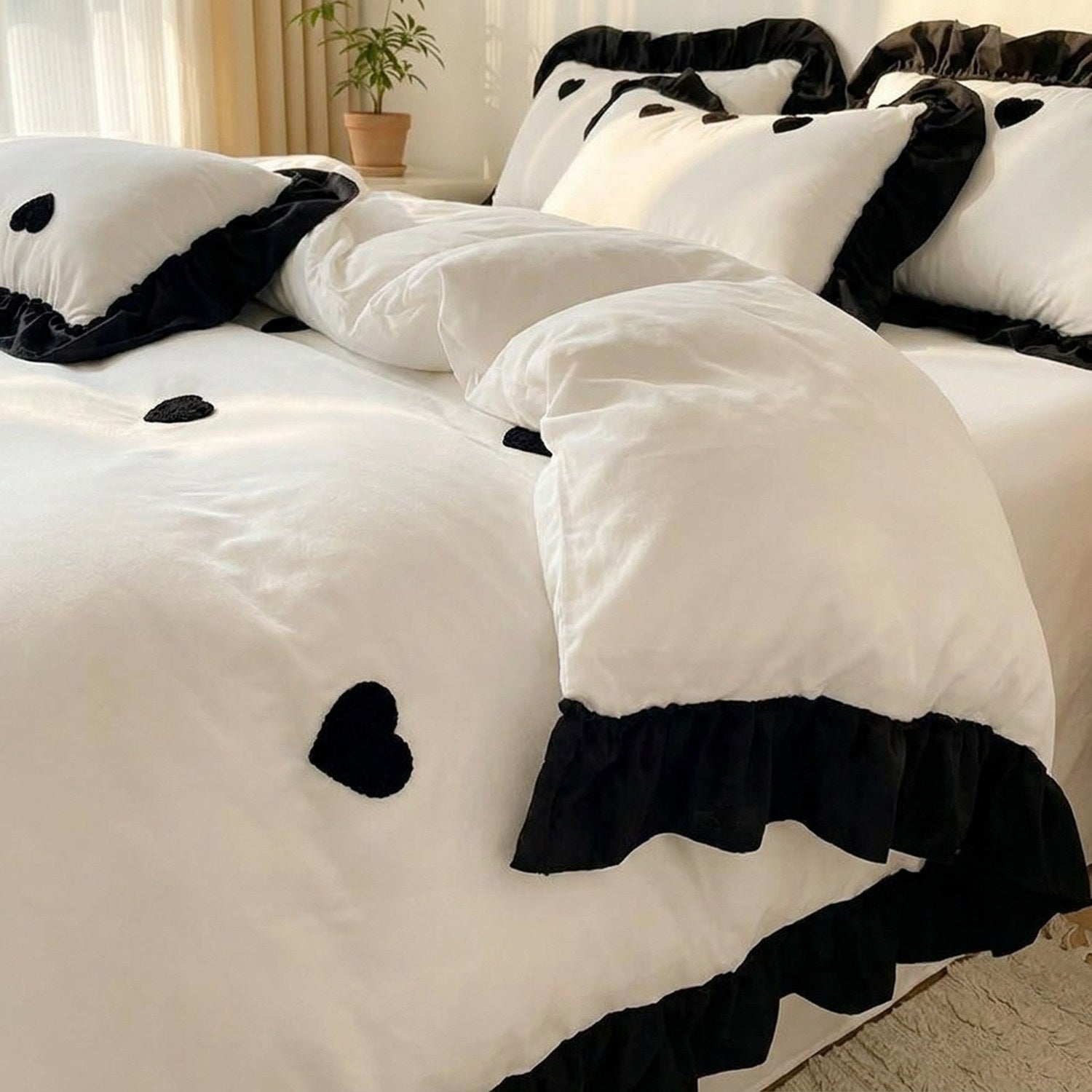 Parure de lit blanche avec housse de couette et taies brodées d un coeur noir sur un lit fait dans une chambre lumineuse