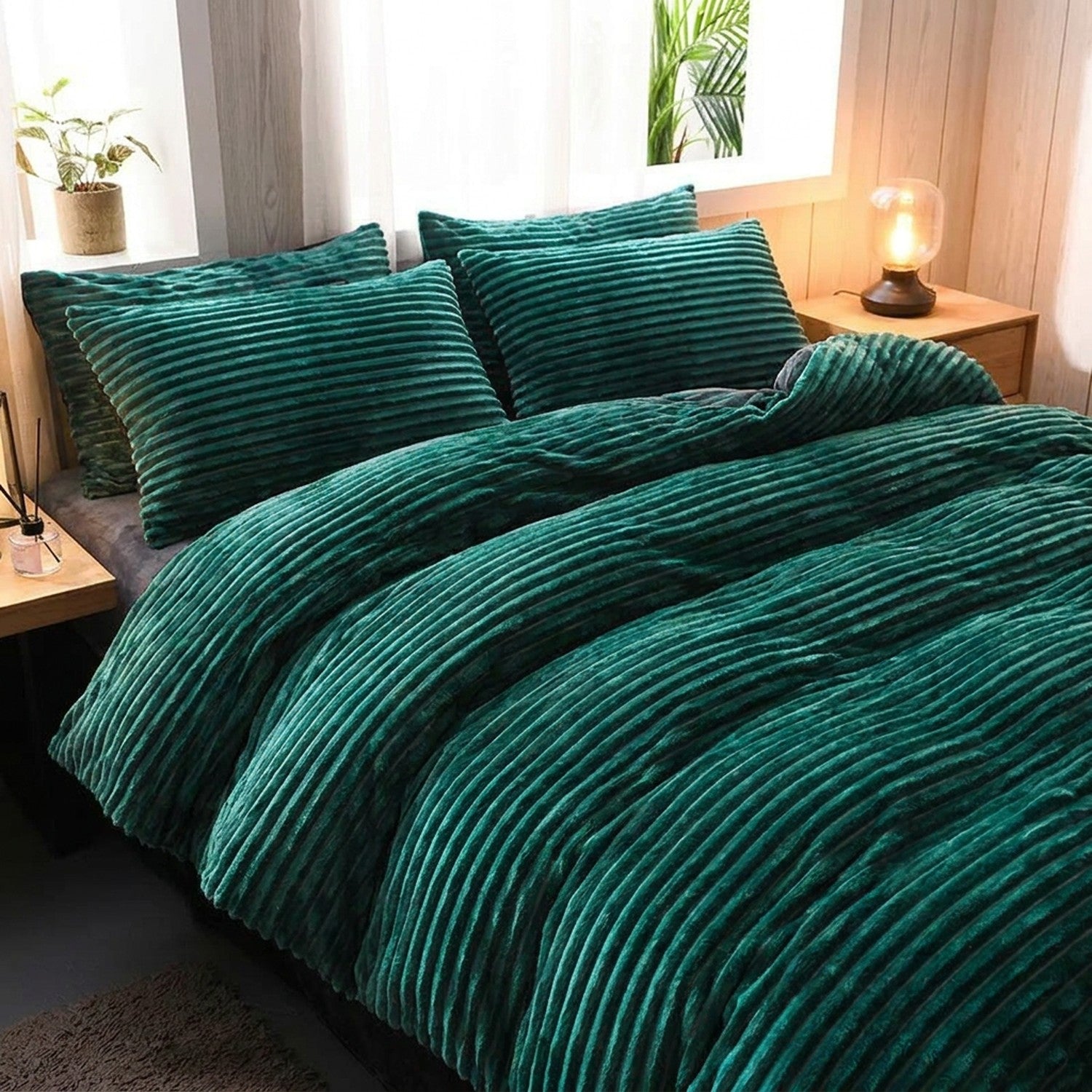 Parure de lit en velours côtelé vert émeraude installée sur un grand lit dans une chambre chaleureuse