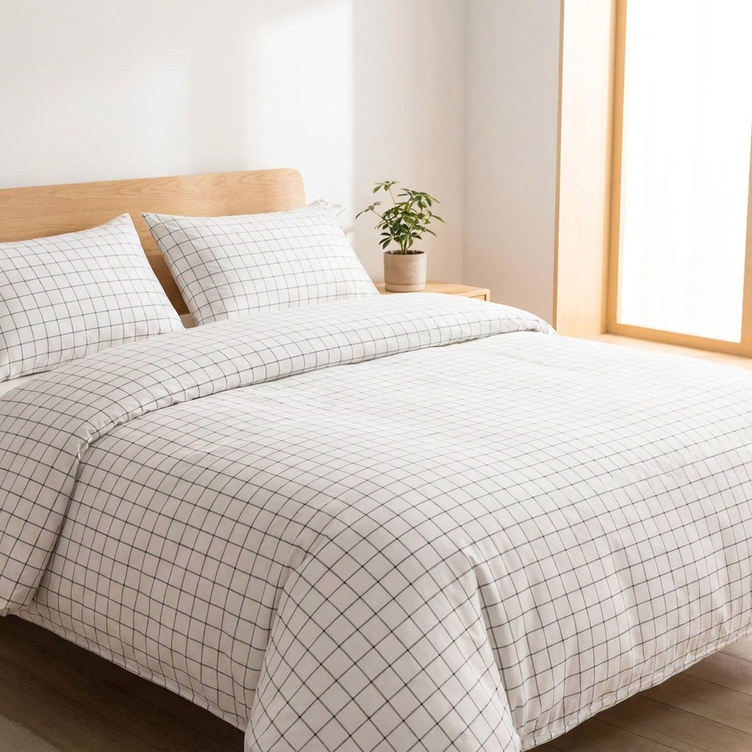 Parure de lit blanche à fines lignes noires installée sur un lit dans une chambre lumineuse