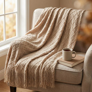 Plaid tricoté beige drapé sur un fauteuil de lecture avec une tasse de thé