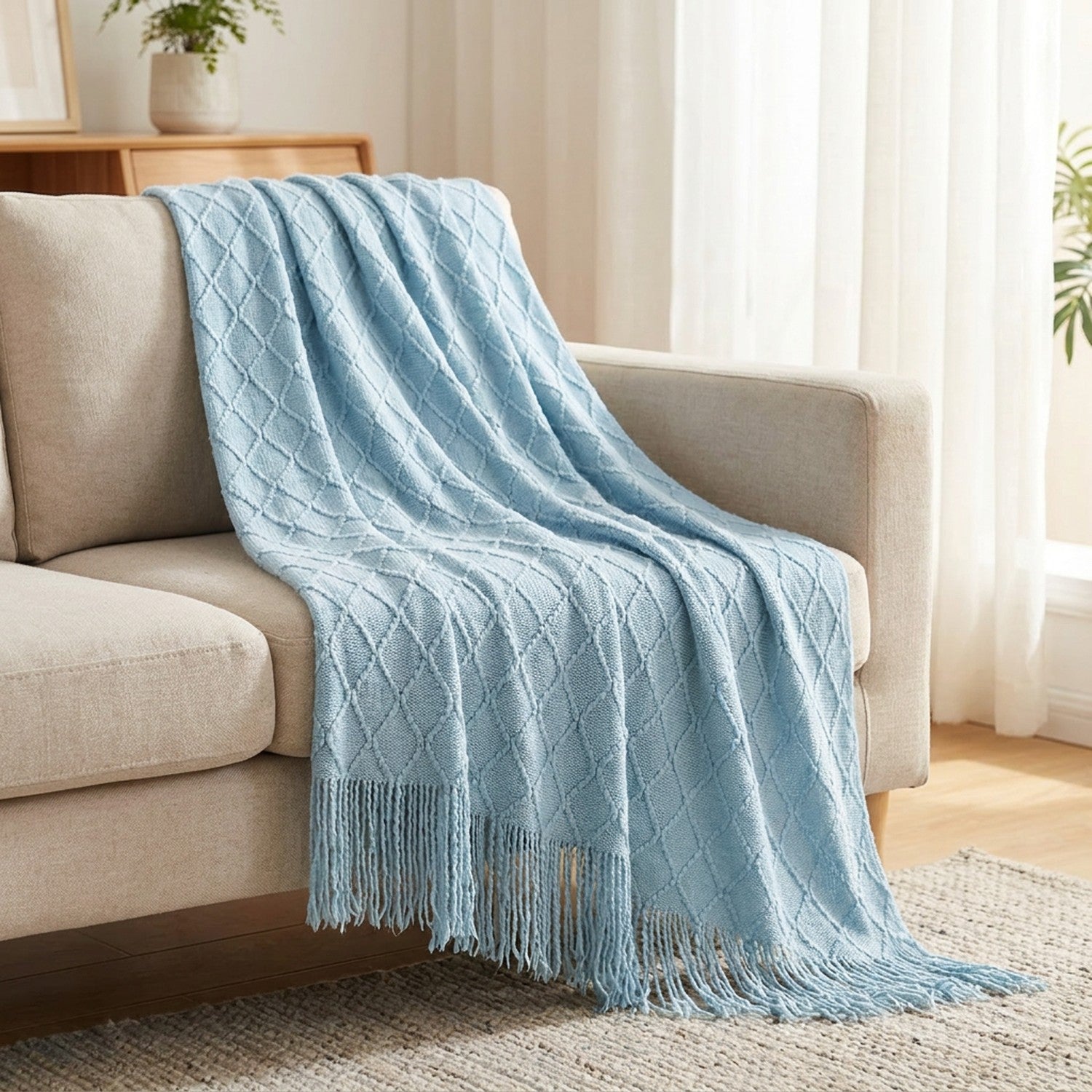 Plaid tricoté bleu à franges drapé sur un canapé cocooning