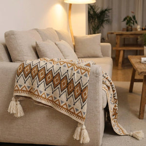 Plaid boho à motif géométrique posé sur un canapé en lin avec coussins