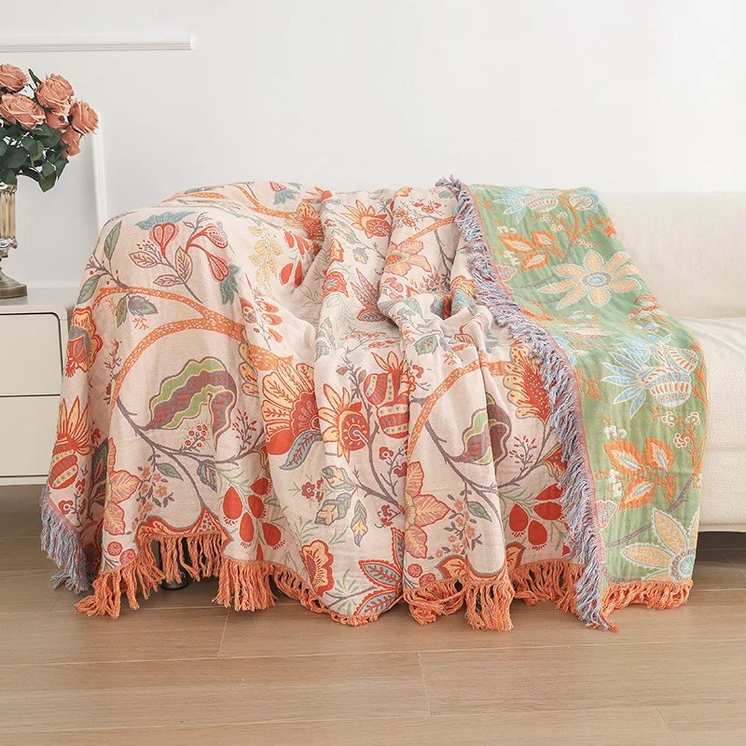 Couverture en coton réversible à motifs floraux orange posée sur un canapé