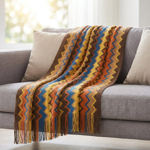 Plaid bohème à chevrons colorés orange plié sur un canapé en lin gris lumineux