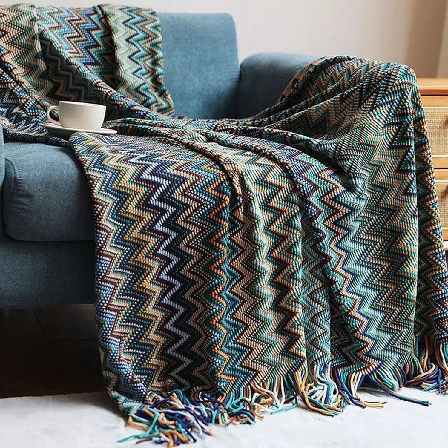 Plaid boho turquoise à chevrons avec longues franges vu de près sur un canapé