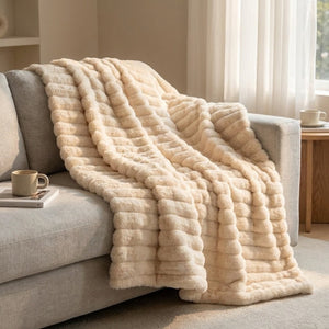 Plaid flanelle épaisse à larges rayures coloris beige drapé sur canapé gris
