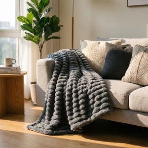 Couverture flanelle à rayures larges étendue sur un lit avec coussins dans une chambre cocooning