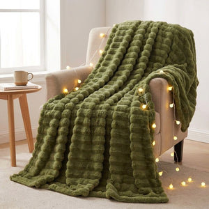 Plaid flanelle épaisse à larges rayures coloris vert olive drapé sur un fauteuil beige avec guirlandes lumineuses