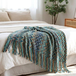 Plaid boho turquoise à franges drapé au pied d'un lit lumineux