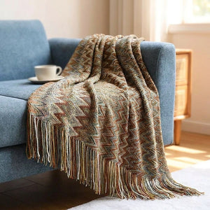 Plaid boho tricoté à chevrons marron et rouille drapé sur un canapé