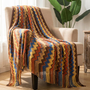 Plaid boho tricoté à chevrons terracotta et multicolores drapé sur un fauteuil