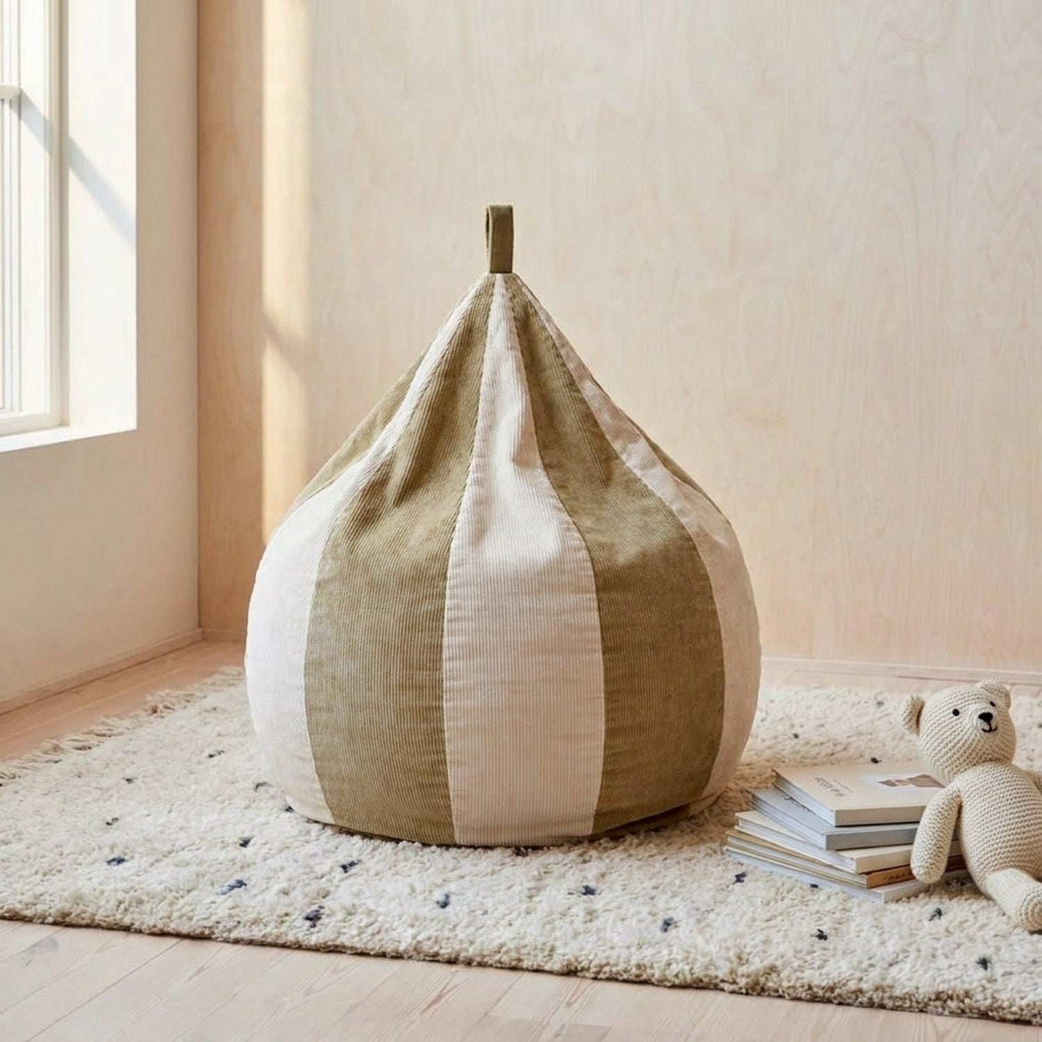 Housse de pouf poire enfant en velours côtelé beige et kaki à rayures posée dans une chambre