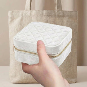 Boîte à bijoux velours blanc tenue en main devant un sac en lin naturel