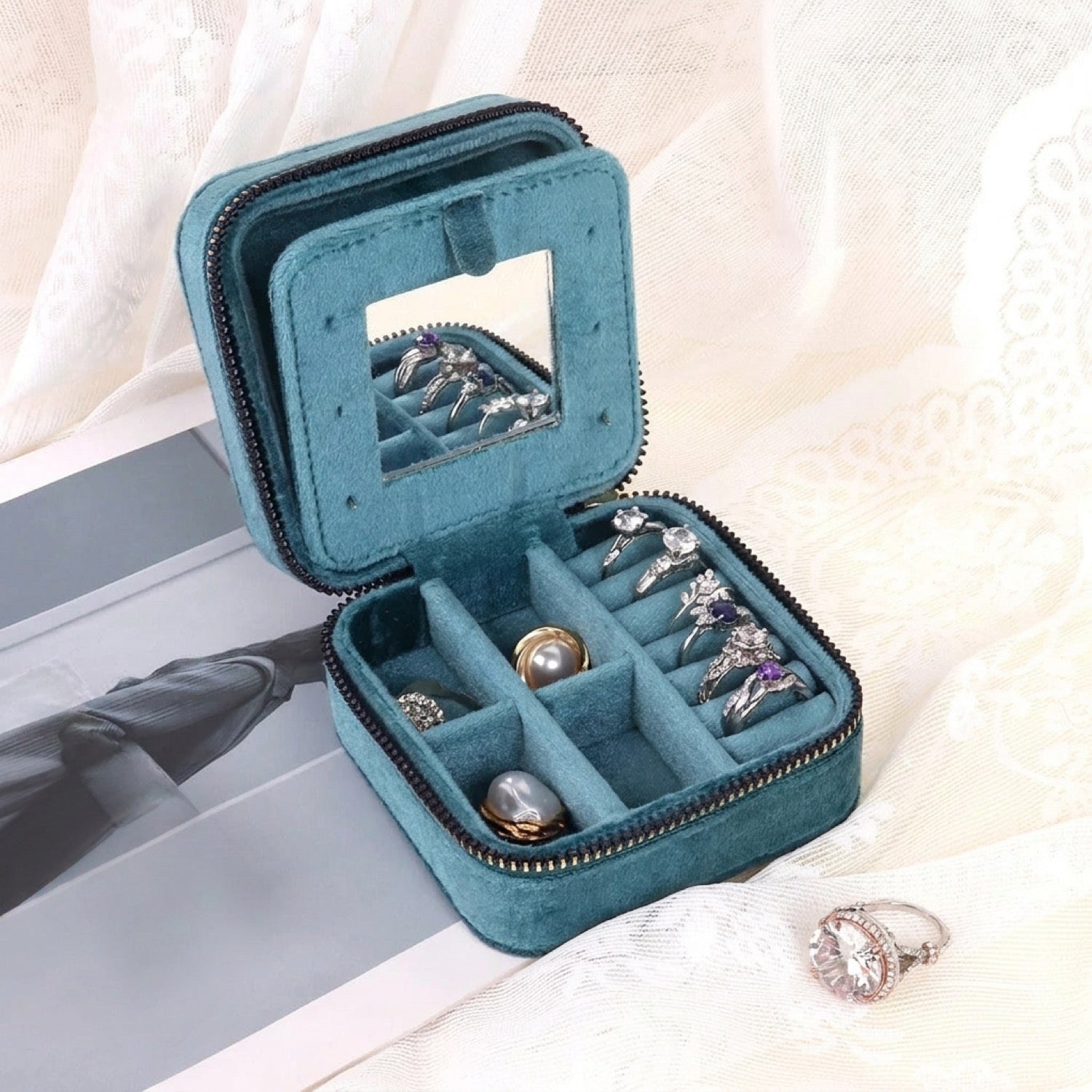 Boîte à bijoux bleu canard ouverte avec miroir et bagues rangées dans les compartiments