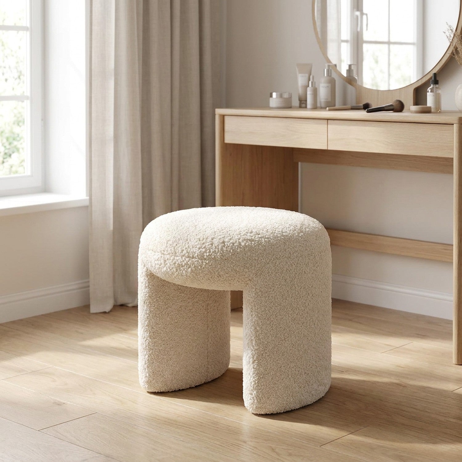 Pouf tabouret bouclé écru devant une coiffeuse dans une chambre lumineuse