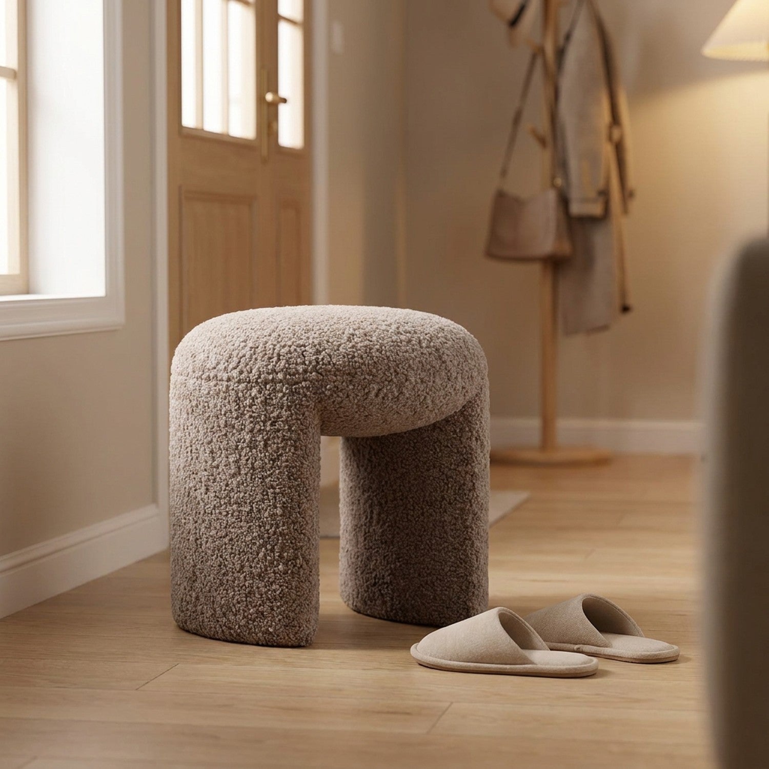 Pouf tabouret bouclé taupe dans une entrée avec des chaussons