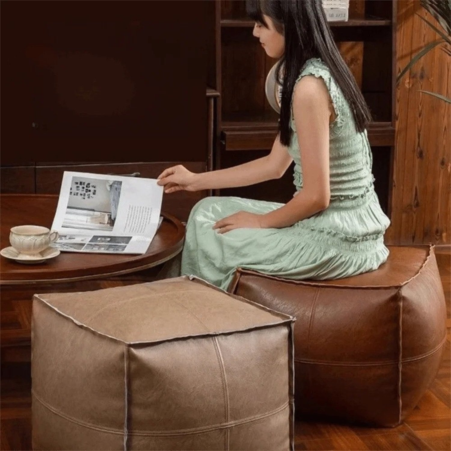 Pouf cube en cuir marron utilisé comme siège d'appoint dans un salon