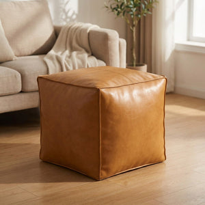 Pouf cube en cuir camel imperméable posé dans un salon chaleureux