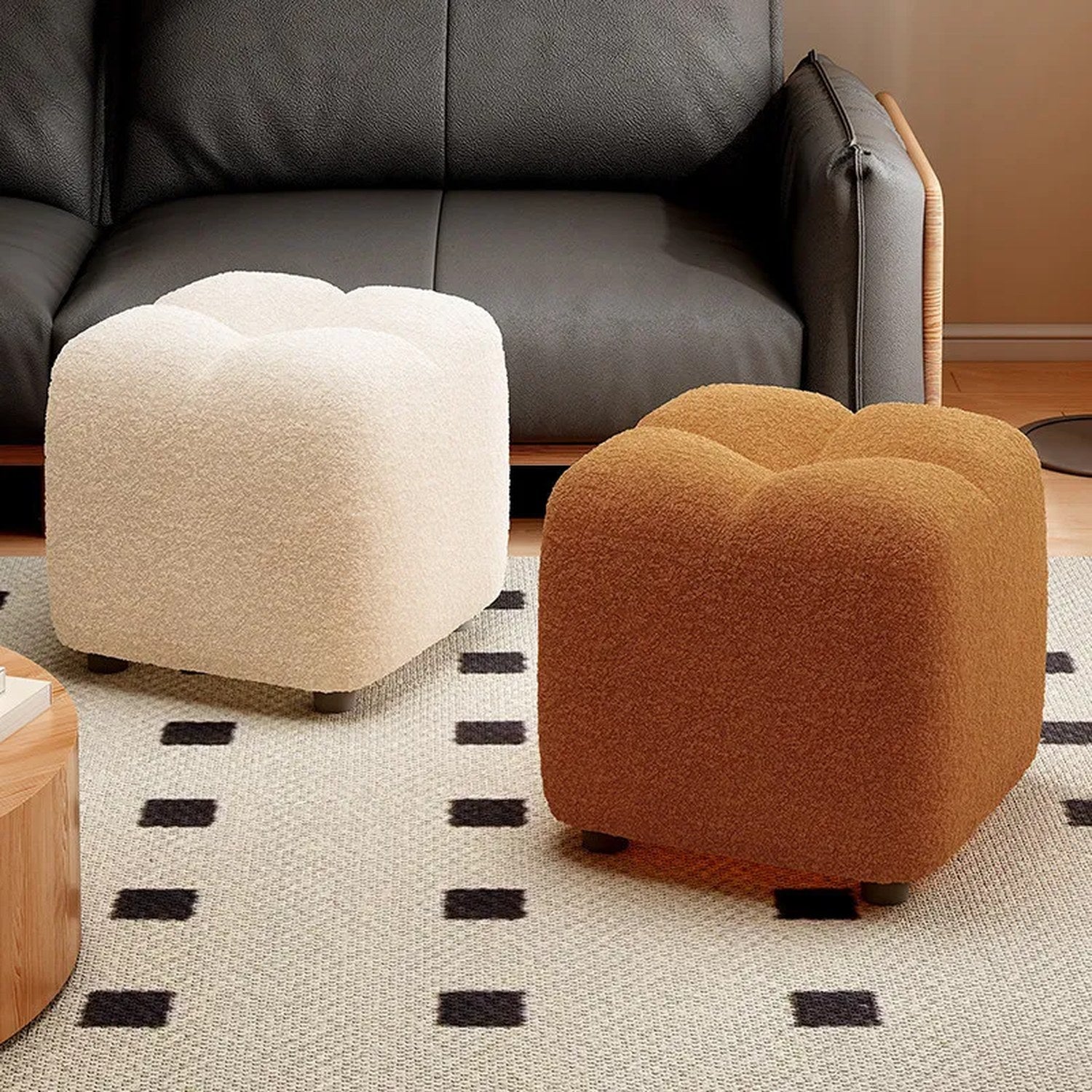 Pouf bouclé blanc et marron placés devant un canapé en cuir noir