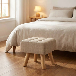 Pouf repose pied capitonné posé au pied d'un lit dans une chambre lumineuse
