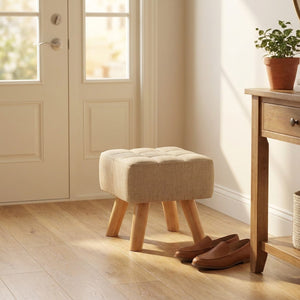 Pouf repose pied capitonné dans une entrée près d'une console et de chaussures