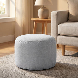 Pouf rond en lin gris dans un salon près d'un canapé
