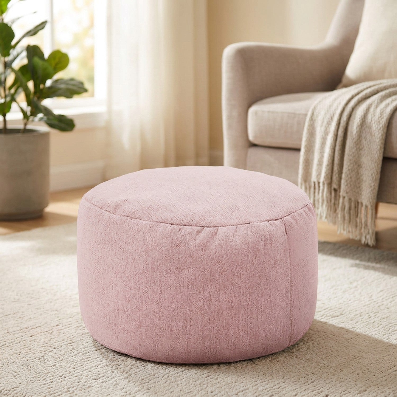 Pouf rond en lin rose en repose-pieds près d'un fauteuil