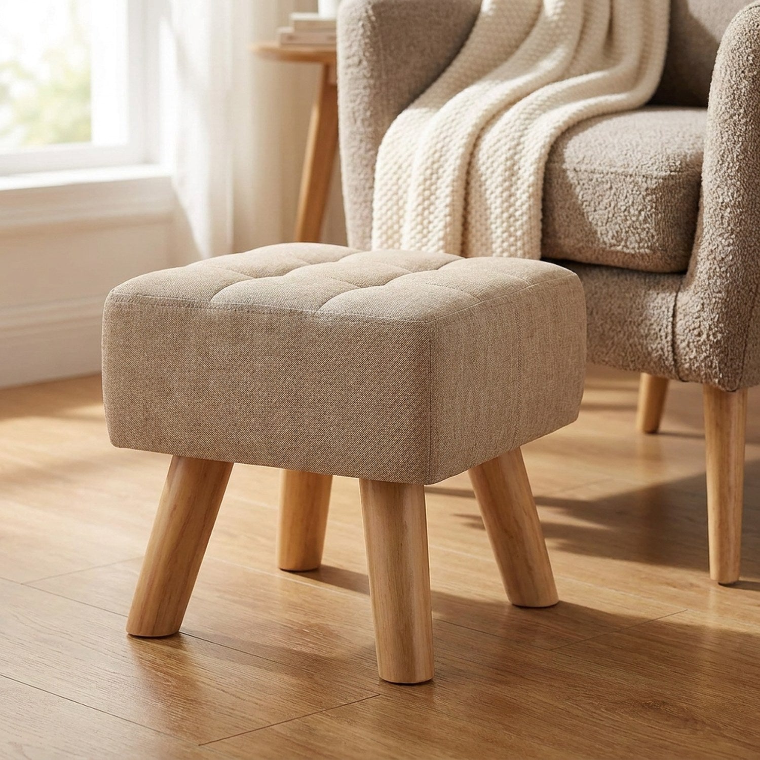 Pouf repose pied capitonné en tissu marron clair avec pieds en bois dans une chambre chaleureuse