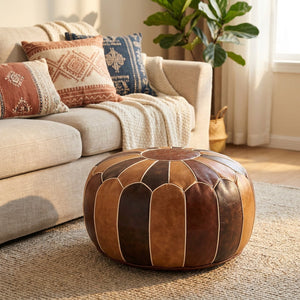 Pouf marocain en simili cuir brun utilisé comme repose-pieds près d'un canapé bohème