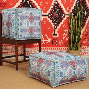 Housse de pouf marocain turquoise à motifs aztèques posée sur tapis berbère
