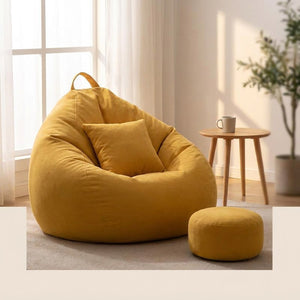 Pouf géant fauteuil poire jaune installé près d'une fenêtre avec repose-pieds assorti dans un salon cosy