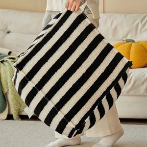 Détail de la housse de pouf rayée noire tenue à la main, non rembourrée