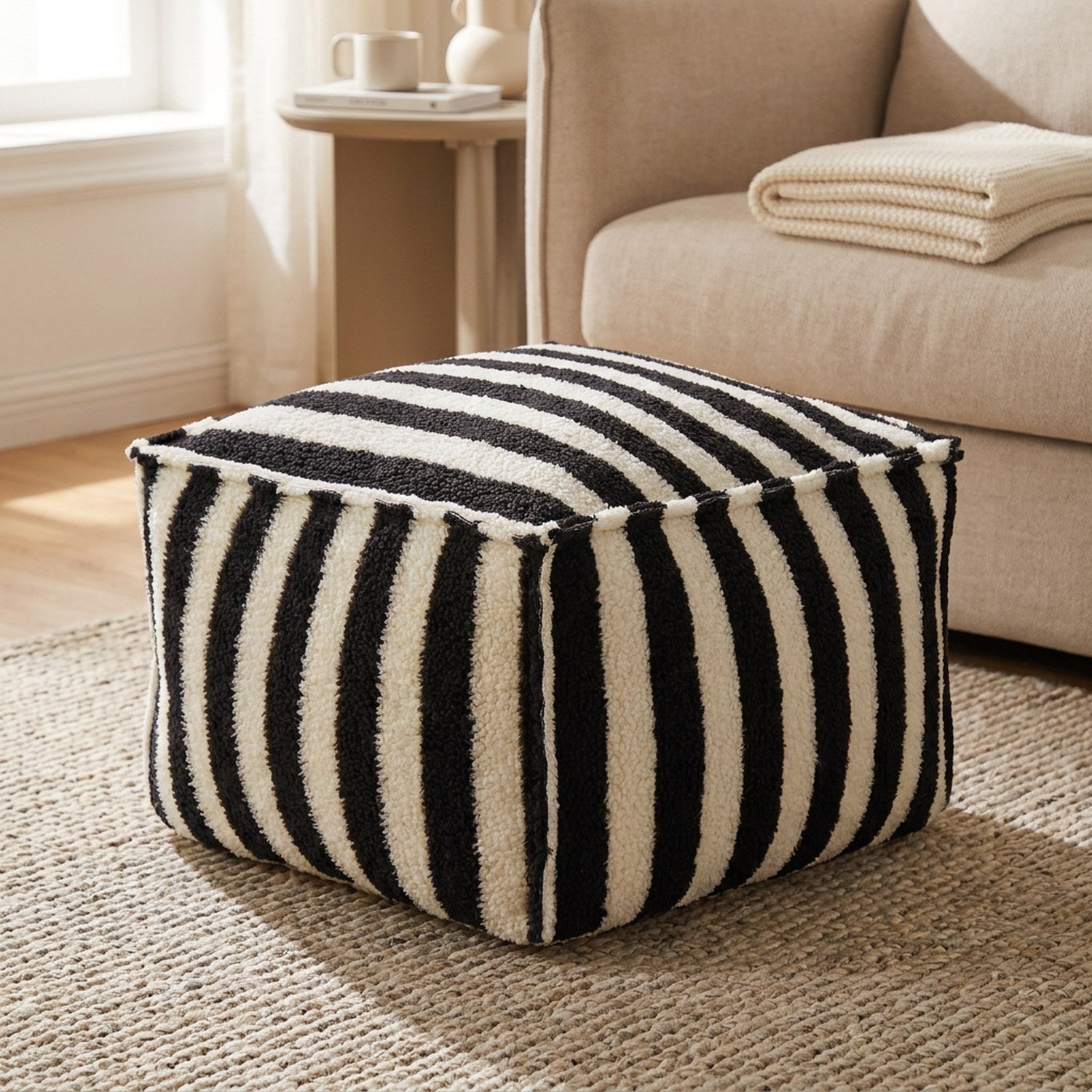 Pouf carré rayé noir et blanc effet laine d'agneau posé au sol dans un salon chaleureux