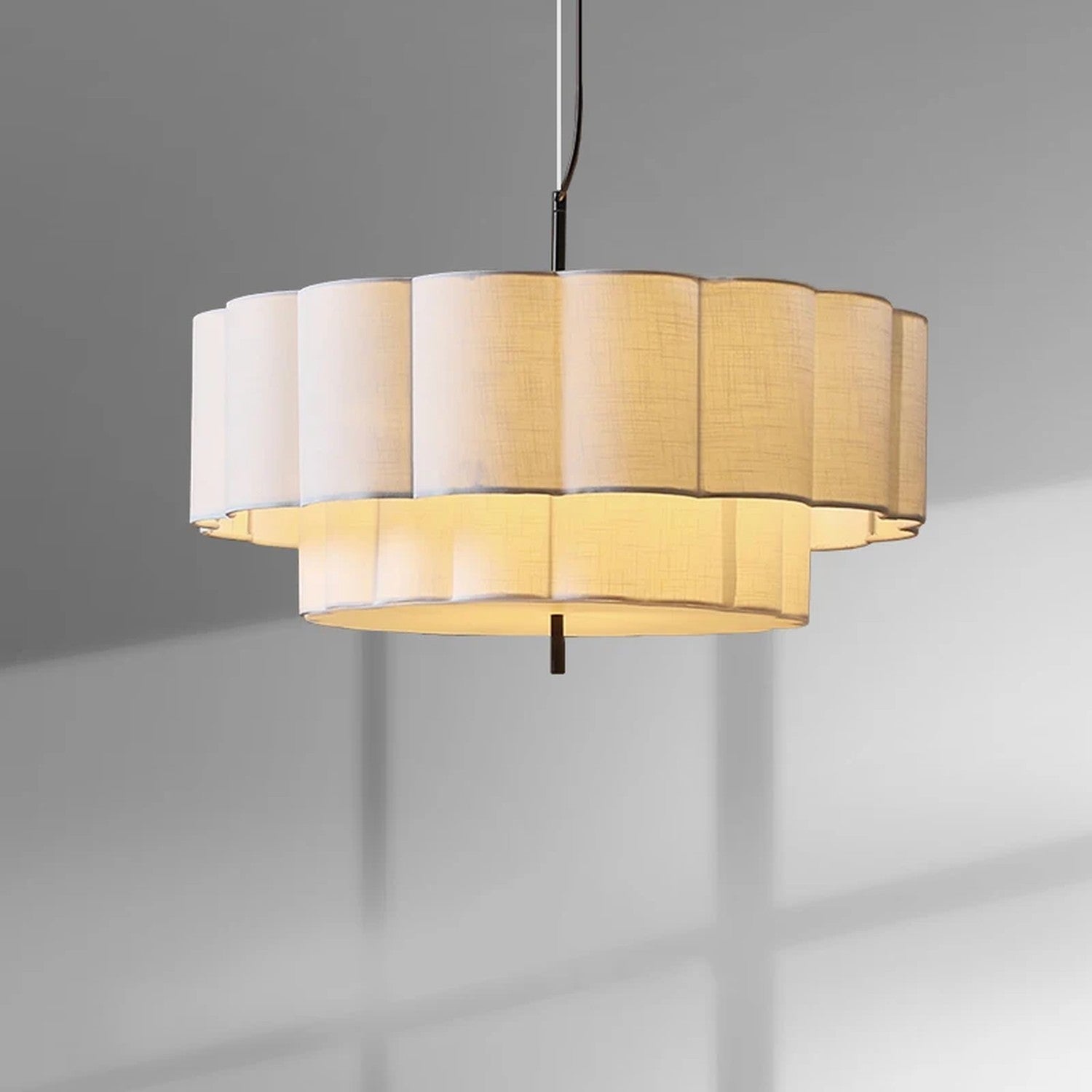 Suspension ronde en tissu beige plissé à deux étages vue de près sur fond neutre