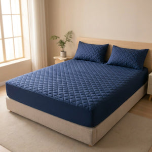 Protège matelas bleu marine installé sur un lit dans une chambre lumineuse