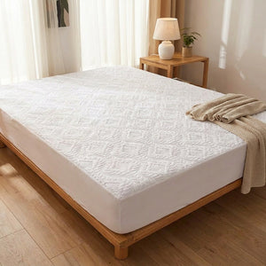 Protège-matelas blanc matelassé sur un lit dans une chambre chaleureuse