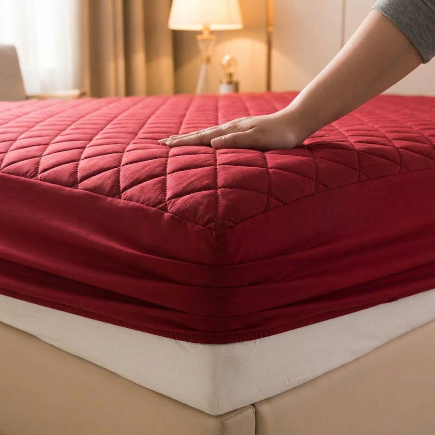 Gros plan sur la surface matelassée et la jupe élastique du protège matelas bordeaux