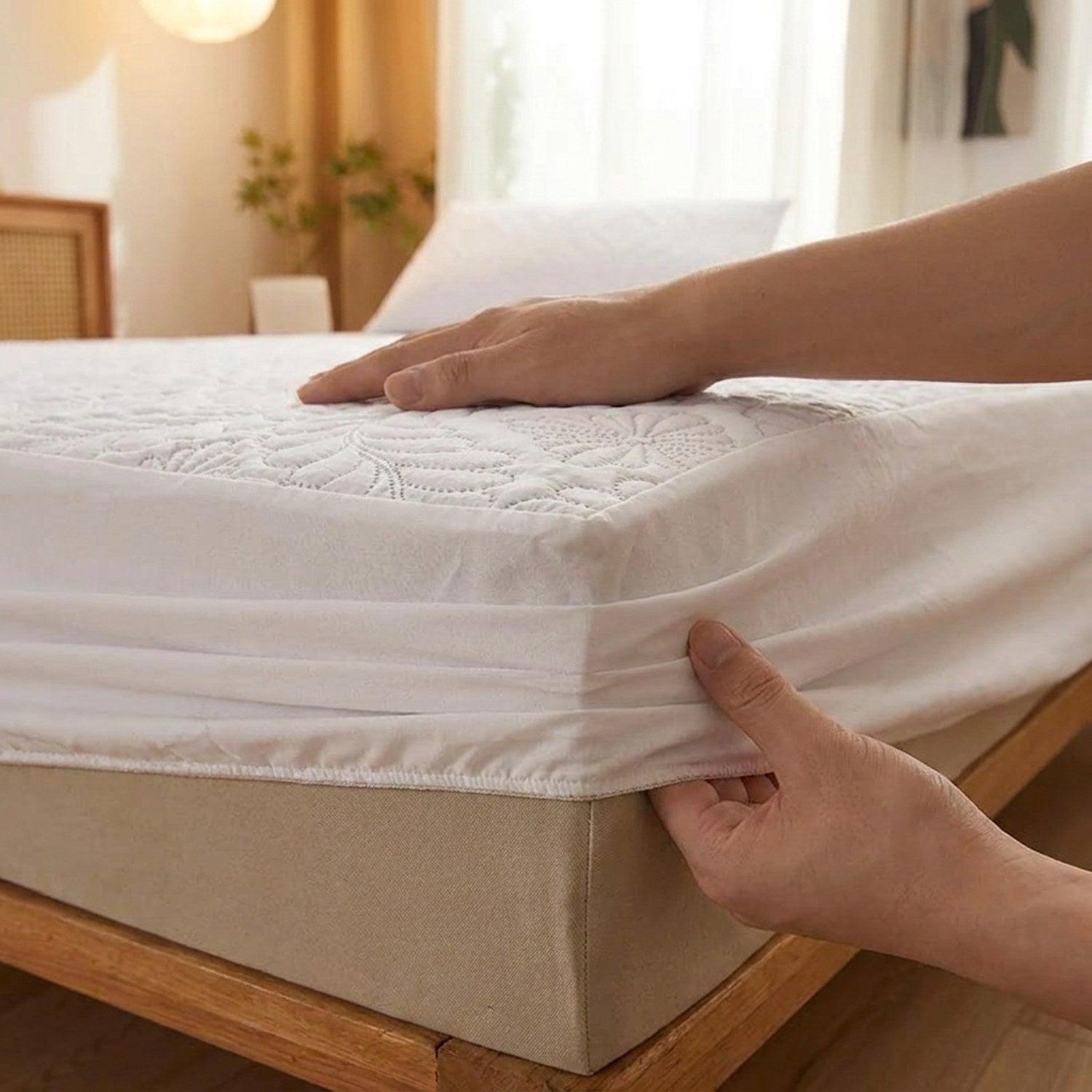Mains ajustant la jupe élastique du protège-matelas blanc sur un matelas