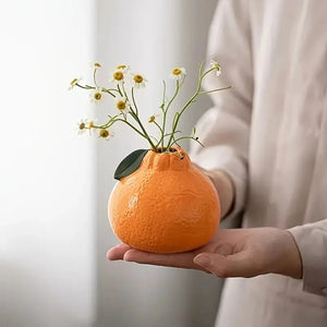 Vase orange en céramique garni de petites fleurs blanches