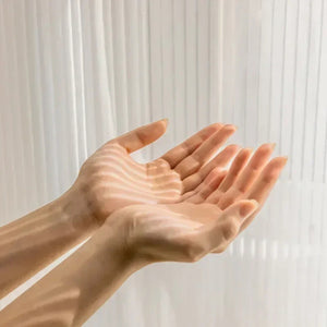 Main derrière le voilage transparent illustrant la légèreté et la translucidité du tulle