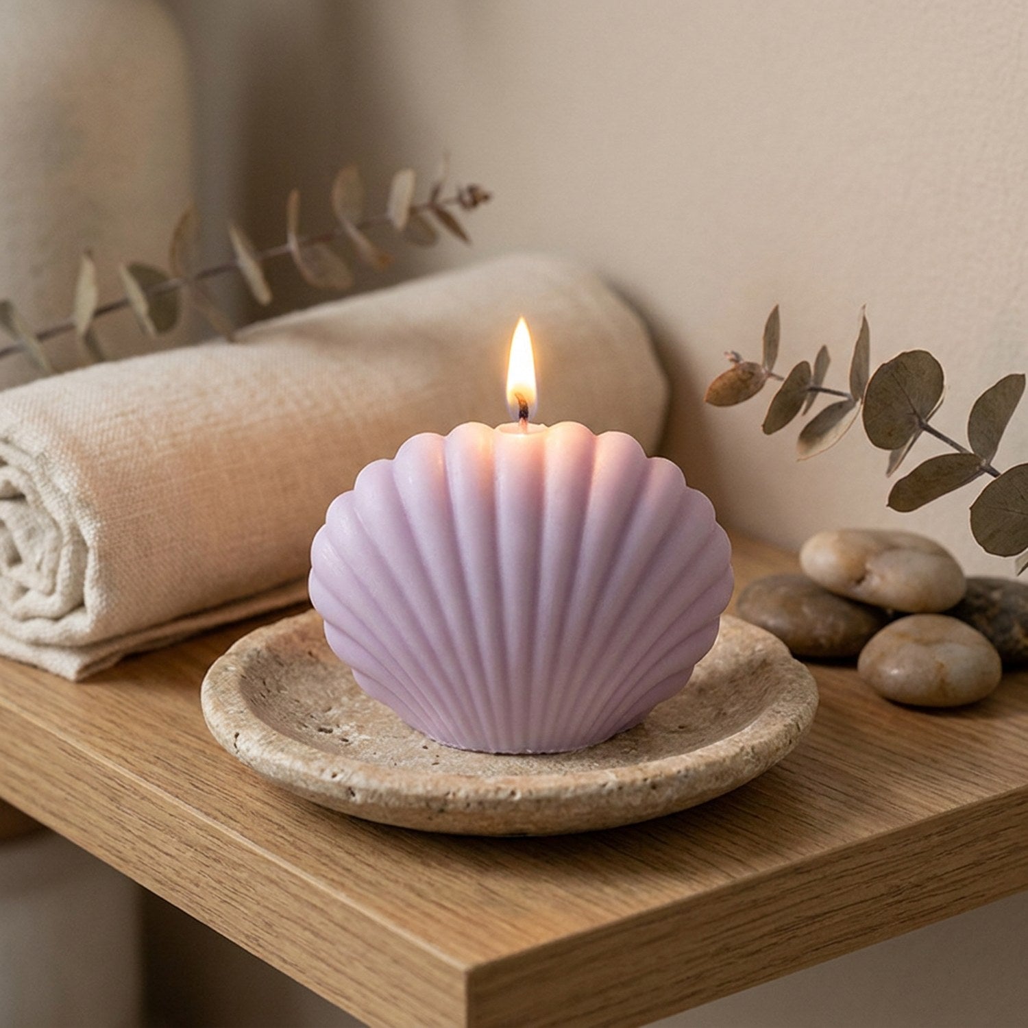 Bougie coquillage violet allumée sur une coupelle en pierre dans une ambiance zen