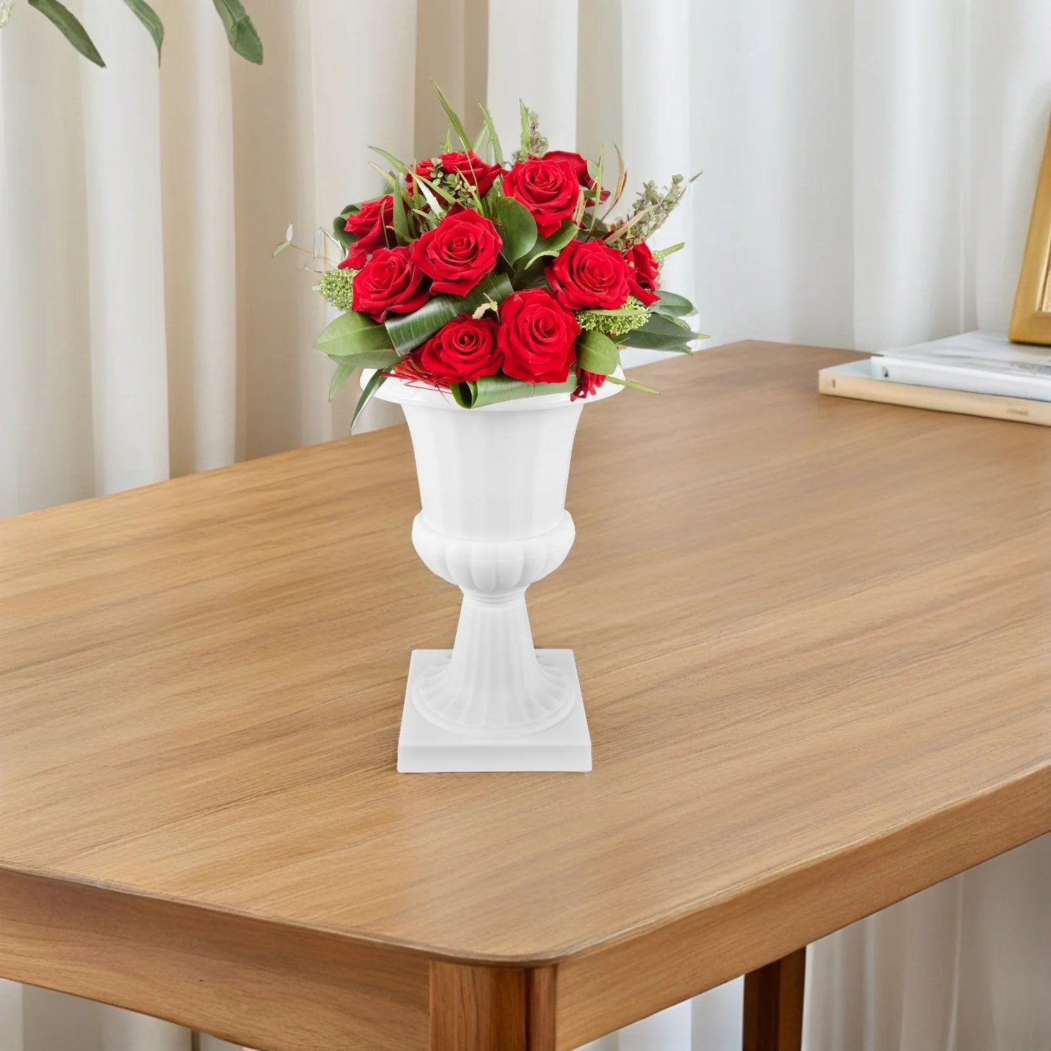 Vase médicis blanc garni de roses rouges sur une table en bois