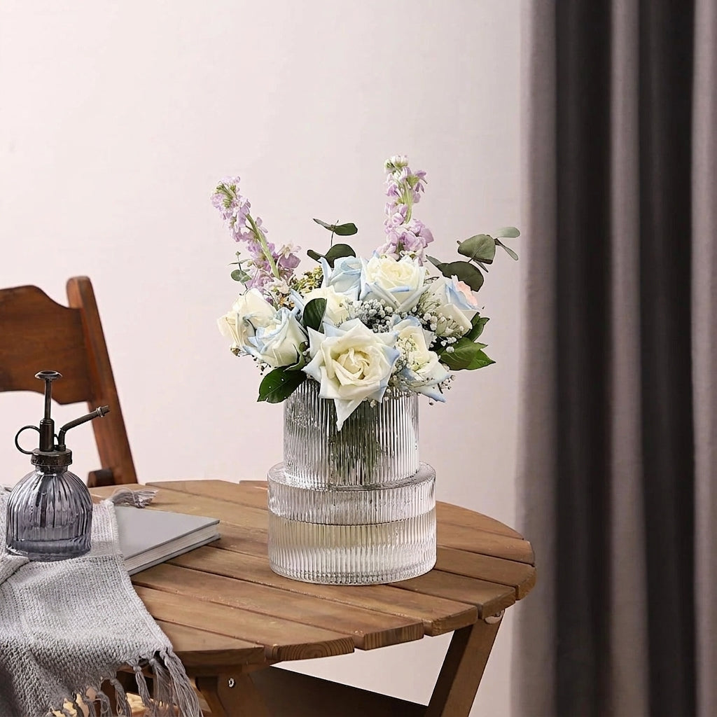 Vase en verre côtelé avec bouquet coloré sur table en bois naturel avec écharpe grise