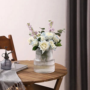 Vase en verre côtelé avec bouquet coloré sur table en bois naturel avec écharpe grise