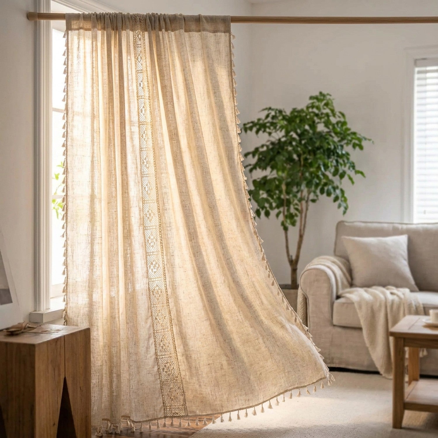 Rideau bohème en lin beige à glands suspendu devant une fenêtre lumineuse dans un salon cosy